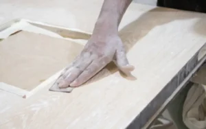 Sanding a door by hand before it goes to the spray booth.